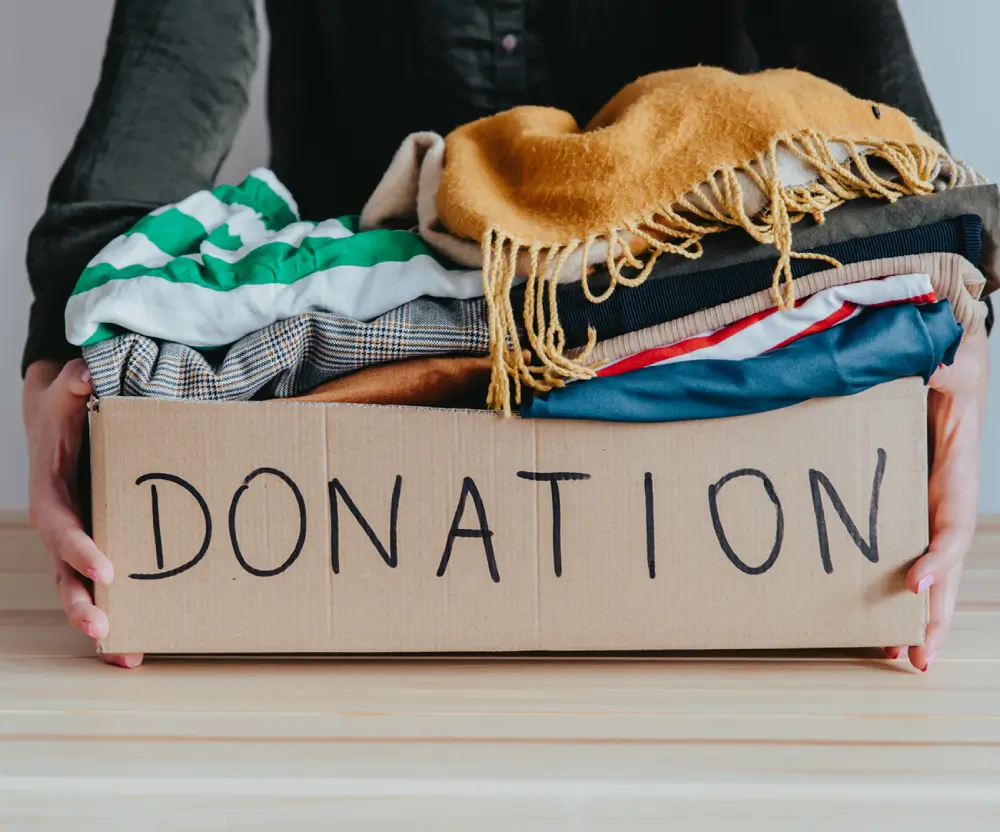 Box of clothes labeled "Donation" being held.