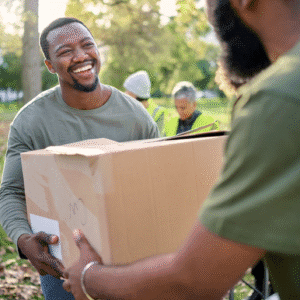 People exchanging a cardboard box outdoors.