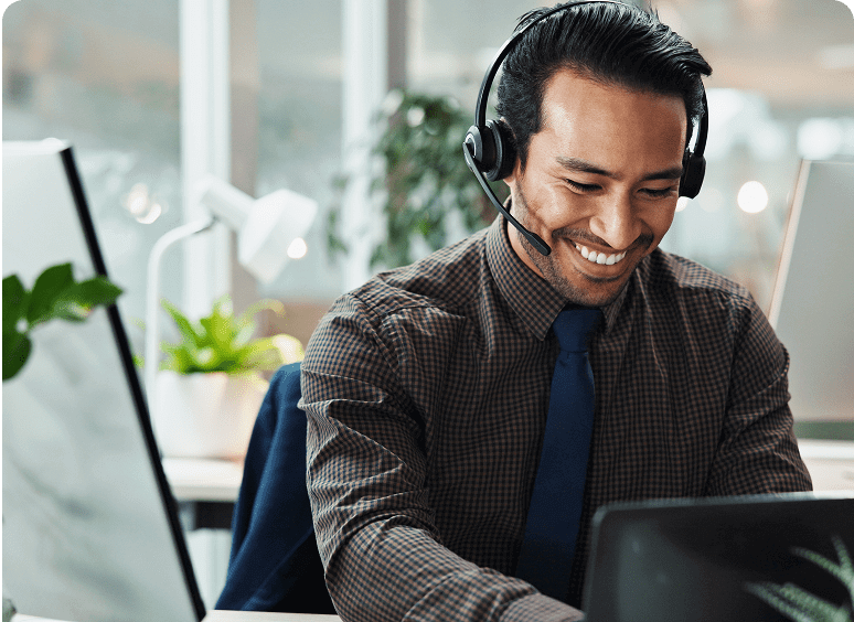 Smiling man wearing headset at office desk.