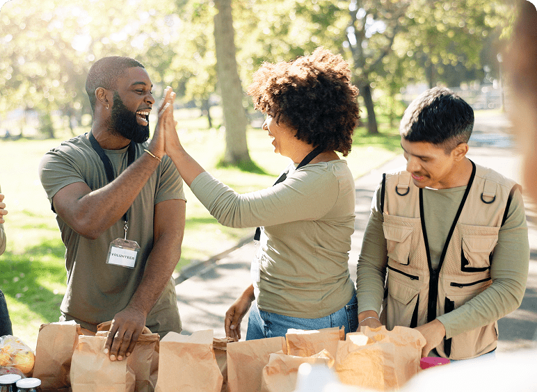 Volunteers high-fiving at outdoor event.